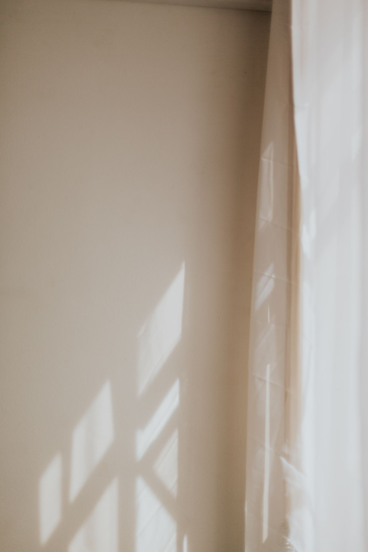 Calming scene of difuse light shining on a wall and white curtain.