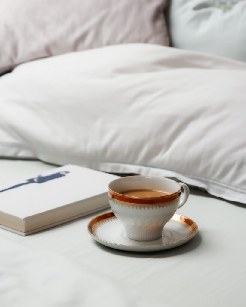 White bed linens, a closed book and a beautifull cup of hot cocoa.